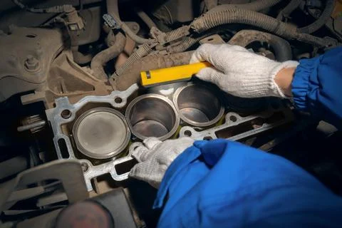 An auto mechanic inspects a car engine with a flashlight. Cylinder block with Stock Photos