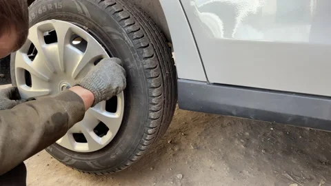 Auto mechanic installs the cap on the wheel of the car Stock Footage 185552252