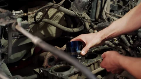 Auto mechanic installs piston using ring compressor tool in engine block for Stock Footage 260718445