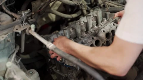 Auto mechanic installs piston using ring compressor into engine block in garage Stock Footage 261990318