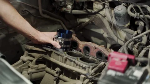 Auto mechanic installs piston using ring compressor into engine block Stock Footage 270422435