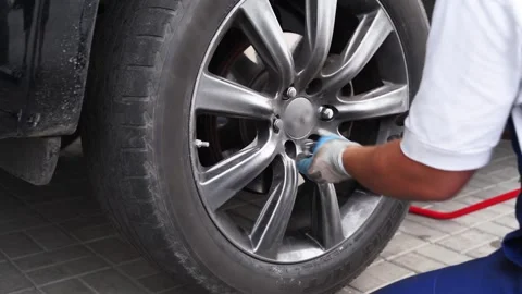 Auto mechanic installs tire using air impact wrench. Professional in garage Stock Footage 265154451