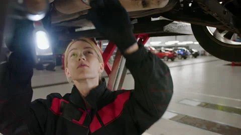 Auto mechanic interferes with the flashlight to the bottom of the car Stock Footage 221548358