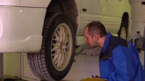 Auto mechanic makes notes on the tablet on the state of the body of the car in Stock Footage 75688084