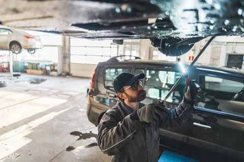 An auto mechanic making chassis inspection at a car workshop, medium shot Stock Photos