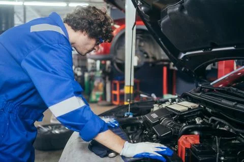 Auto mechanic man checking and repairing car at repair shop Stock Photos