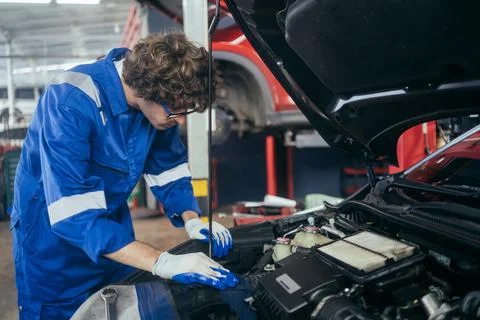 Auto mechanic man checking and repairing car at repair shop Stock Photos