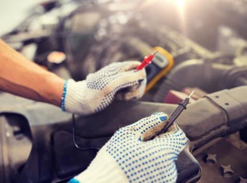 Auto mechanic man with multimeter testing battery Stock Photos