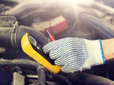 Auto mechanic man with multimeter testing battery Stock Photos