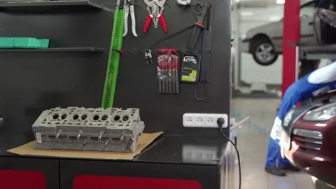 Auto mechanic performs engine overhaul in workshop. Cylinder head on bench Stock Footage 272172382