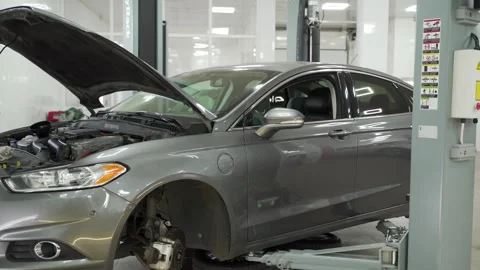 Auto mechanic performs routine vehicle maintenance in well-equipped garage Stock Footage 271595603