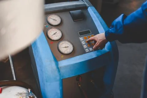 Auto mechanic presses a button on the machine to refuel air conditioners Stock Photos