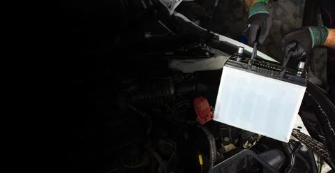 Auto mechanic is pulling up an car old battery for replacement, copy space Stock Photos