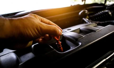 The auto mechanic pulls the dipstick to check the engine oil level Stock Photos