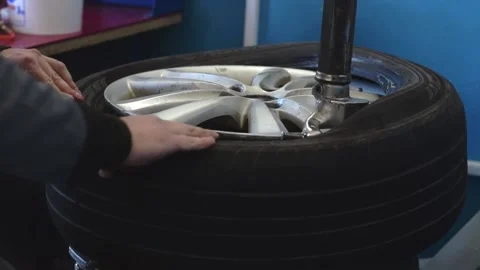 Auto mechanic puts a new tire on a car disc using a tire fitting machine. Stock Footage 169944281