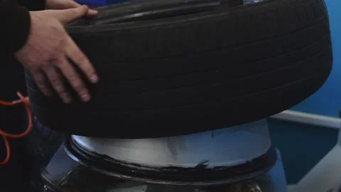 Auto mechanic puts a new tire on a car disc using a tire fitting machine. Stock Footage 169944452
