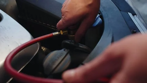 Auto mechanic puts on the valve to refill the car air conditioner with freon Stock Footage 284545533