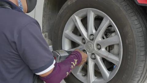 Auto mechanic putting the wheel lug nuts back on Stock Footage 239744554