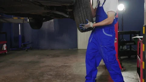 Auto mechanic is putting wheels on a car in a garage. Stock Footage 208824971