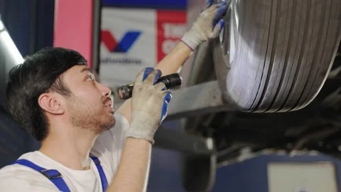 Auto mechanic is putting wheels on a car in a garage. Stock Footage 229484807