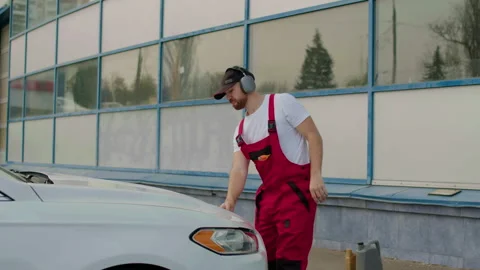 Auto mechanic in red overalls inspecting engine and fluid levels under the hood Stock Footage 312517697