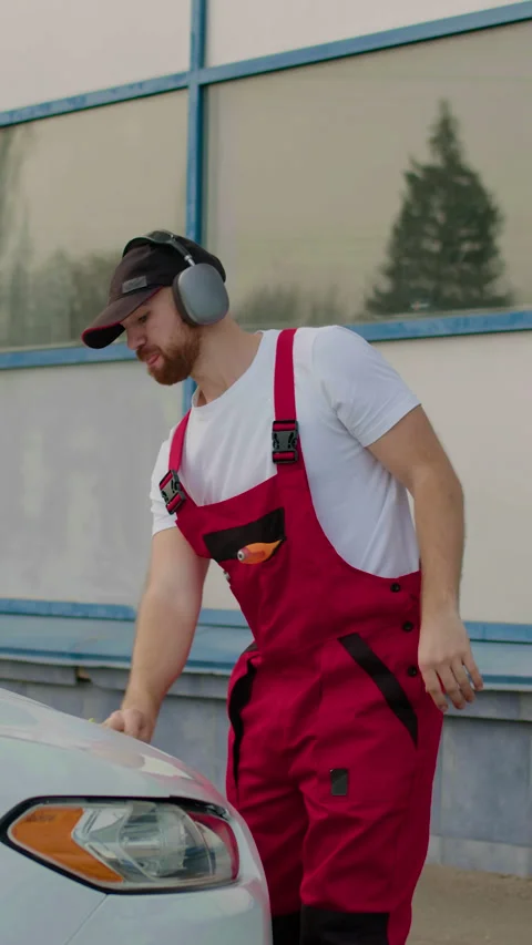 Auto mechanic in red overalls inspecting engine and fluid levels under the hood Vídeos de archivo 320958825