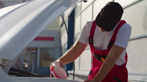 Auto mechanic in red overalls performing under-the-hood check, inspecting engine Stock Footage 312517759