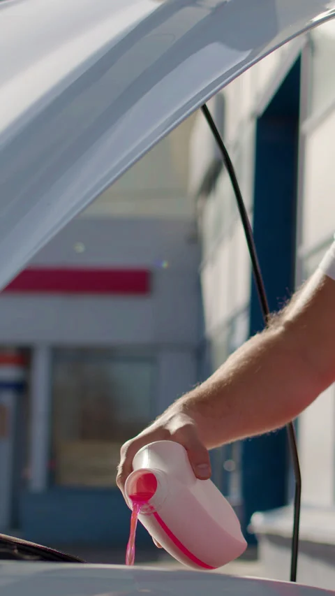 Auto mechanic in red overalls performing under-the-hood check on a car Stock Footage 320393876