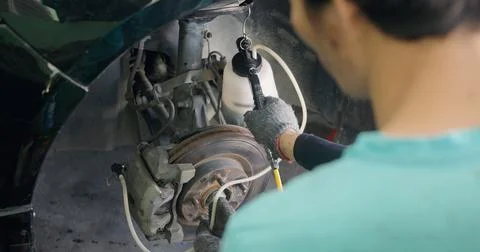Auto mechanic replacing brake fluid on a vehicle 스톡 사진