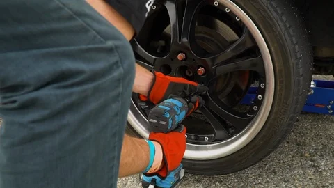 Auto mechanic with screwdriver changing car tire Stock Footage 127639400