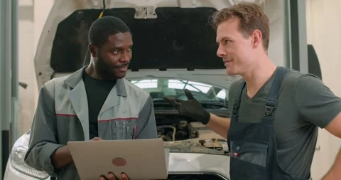 Auto mechanic showing data on the computer for colleague Stock Footage 259626837
