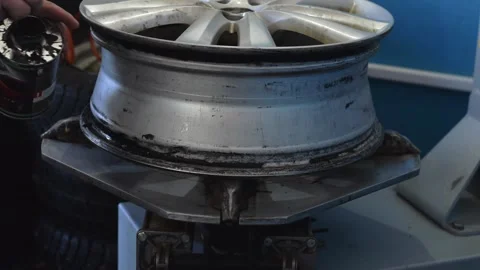 An auto mechanic smears a car disc with a sealant when installing a tire. Stock Footage 169944186