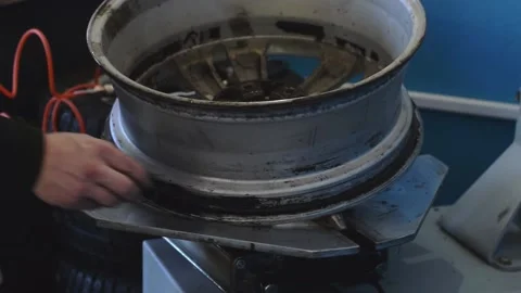 An auto mechanic smears a car disc with a sealant when installing a tire. Stock Footage 169944341