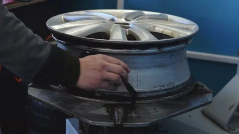An auto mechanic smears a car disc with a sealant when installing a tire. Stock Footage 169944392