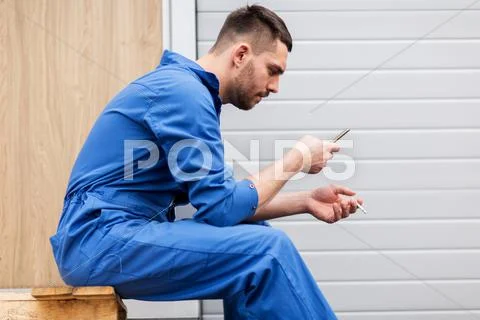 Auto mechanic smoking cigarette at car workshop Stock Photos