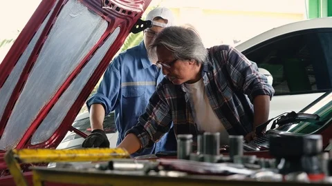 Auto mechanic talking to old man customer about engine servicing at garage. 動画素材 122266838