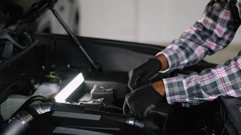 Auto mechanic tightening engine components under work lamp Stock Footage 300610176