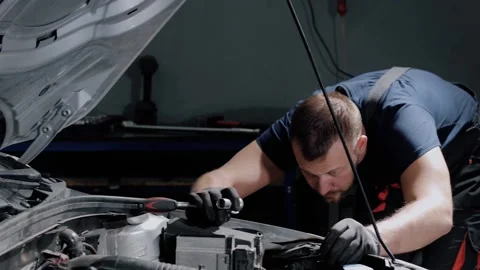 Auto mechanic twisting bolts to remove gearbox for repair in modern car.  Stock Footage 239471057