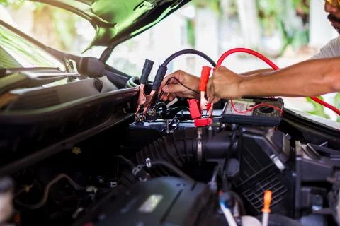 Auto mechanic use voltmeter to check voltage level in car battery. Auto mecha Stock Photos