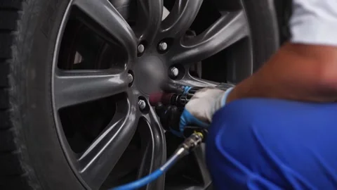 Auto mechanic uses air jack to lift vehicle, swiftly removes tire with pneumatic Video stock 268620009