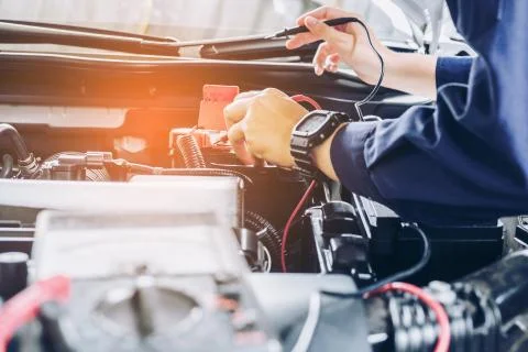Auto mechanic uses a multimeter voltmeter to check the voltage level in a car Stock Photos