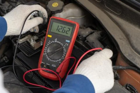 An auto mechanic uses a multimeter voltmeter to check the voltage level in a  Stock Photos