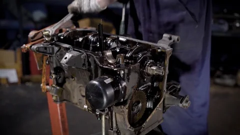 Auto mechanic is using big wrench and spinning bolts inside a used car engine Stock Footage 84146649