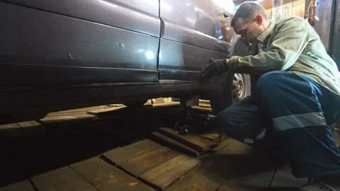 Auto mechanic using car jack to change tires at workshop. Stock Footage 326067339