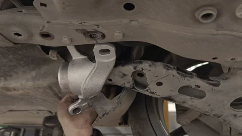 Auto Mechanic Using a Hammer While Working Beneath a Vehicle Chassis Stock Footage 329452167