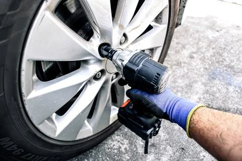 Auto mechanic using impact wrench cordless to change car wheel Stock Photos