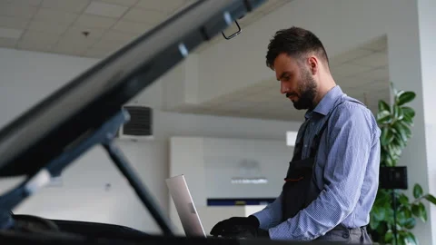 Auto mechanic using laptop for vehicle diagnostics in garage Stock Footage 300612784