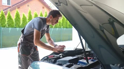 Auto mechanic using laptop for vehicle diagnostics in garage Stock Footage 313464439