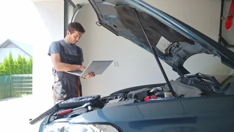 Auto mechanic using laptop for vehicle diagnostics in garage Stock Footage 313838585