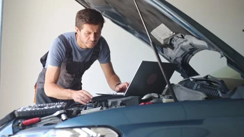 Auto mechanic using laptop for vehicle diagnostics in garage Stock Footage 314253011